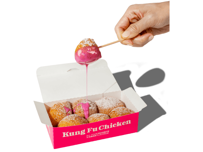A shareable box of warm Kung Fu Donuts, dusted with powdered sugar and served with a vibrant, sweet pink dipping sauce.